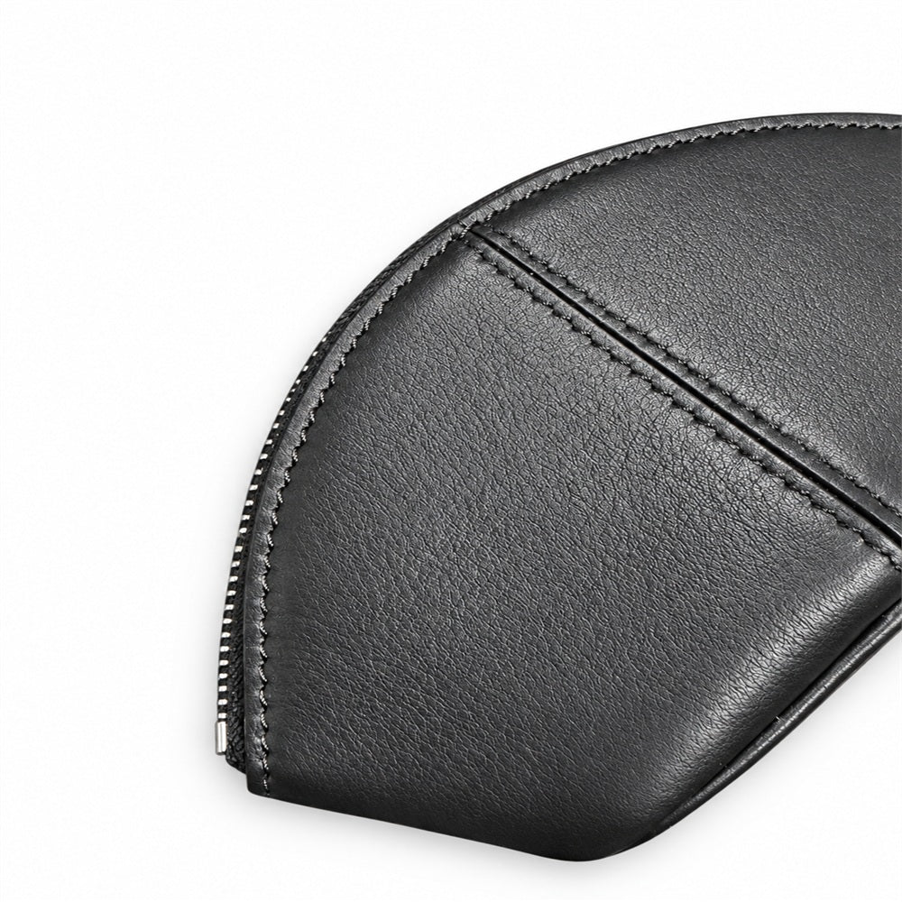 Close-up of the shell-shaped pouch's black textured surface, center seam and edge stitching.
