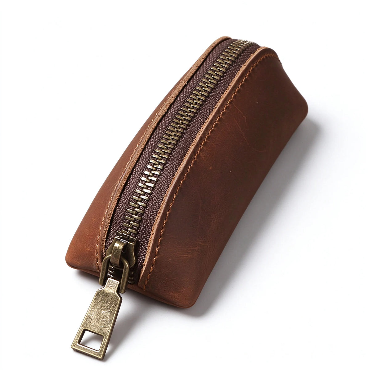 Close-up of the antique-brass-tone zipper and contrast stitching on a brown leather key pouch.