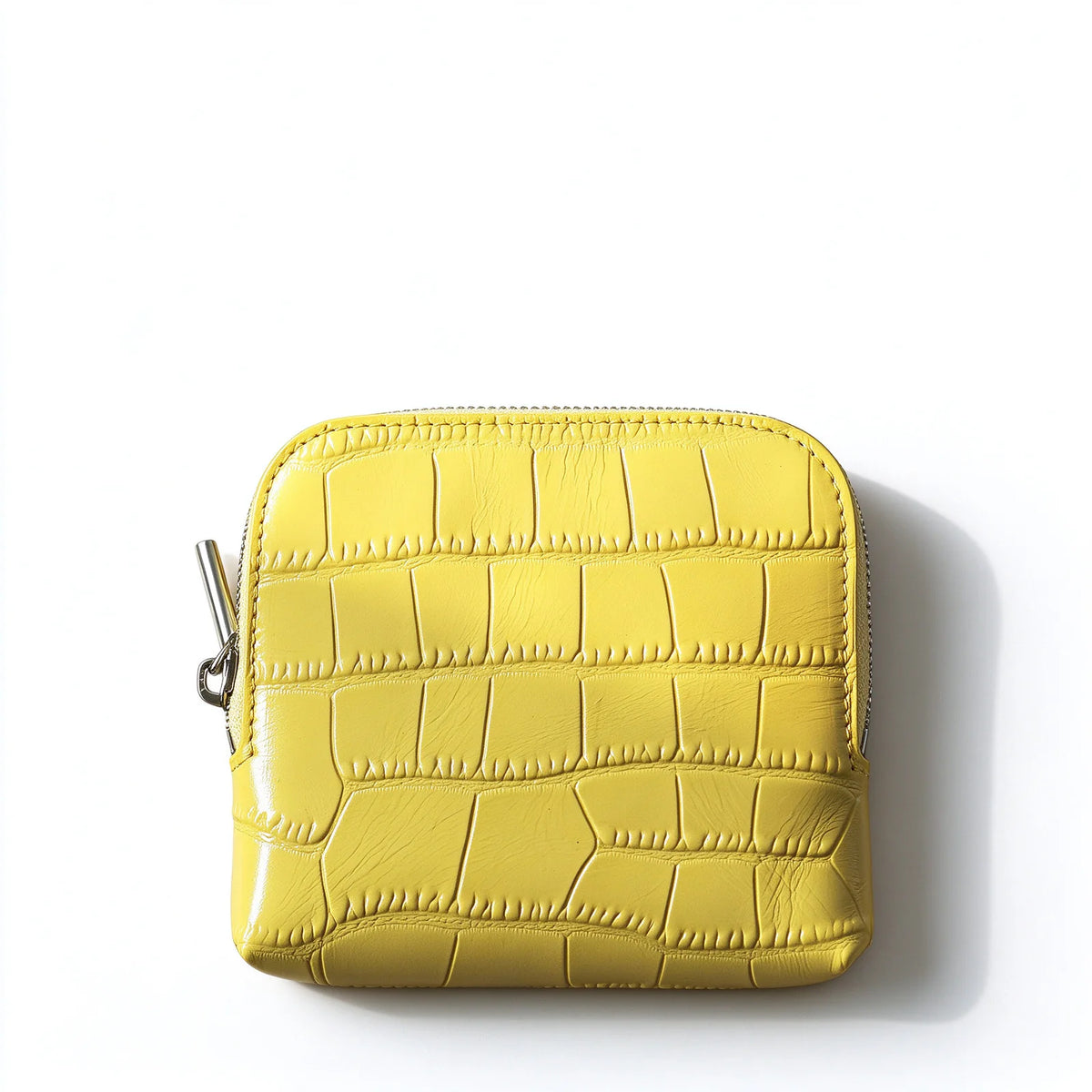Front view of a yellow crocodile-textured leather jewelry pouch with rounded corners and a silver-tone zip pull.