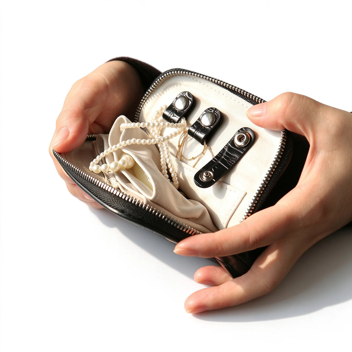 Open black leather jewelry pouch showing a pale interior, snap-fastened loops and necklaces inside.