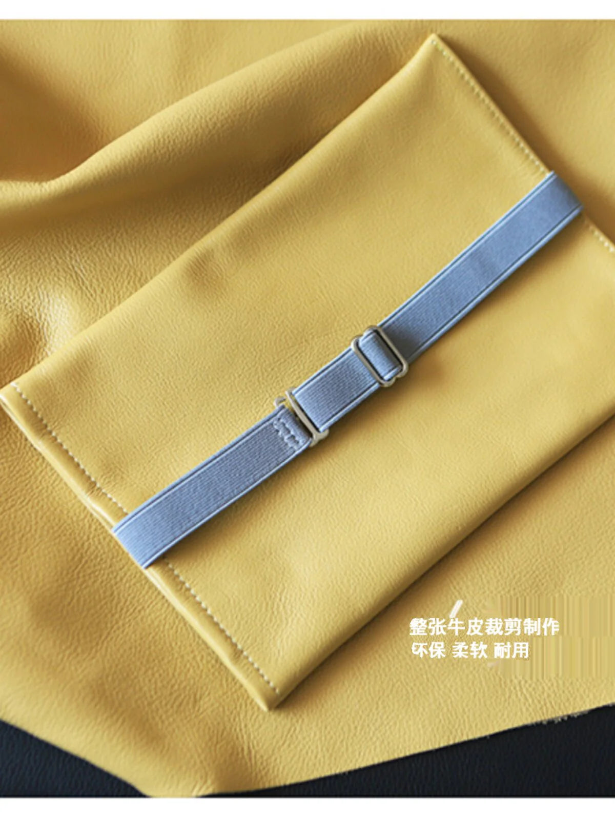 Back of a yellow leather tissue holder showing the adjustable grey strap and edge stitching