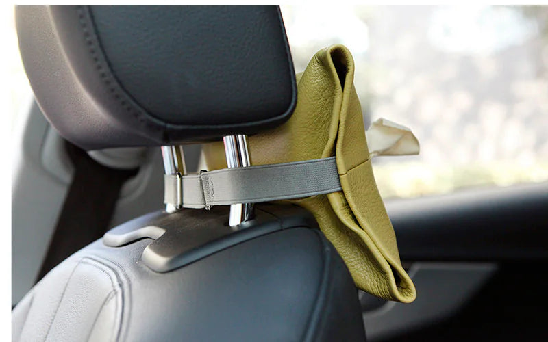 Side view of a yellow leather tissue holder attached around car headrest posts with a grey strap