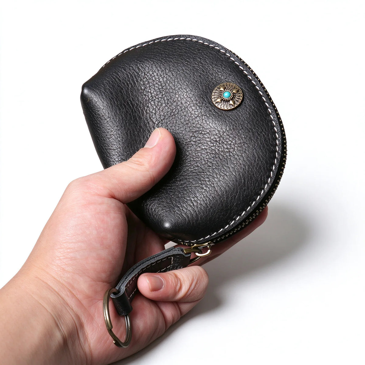 Black leather key and coin pouch held in one hand with contrast stitching and a round front ornament