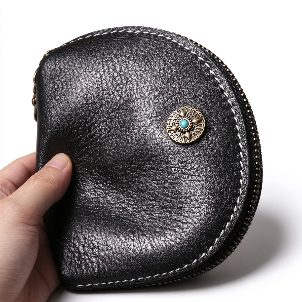 Close-up of a black leather key pouch with a round metal ornament and turquoise-coloured centre