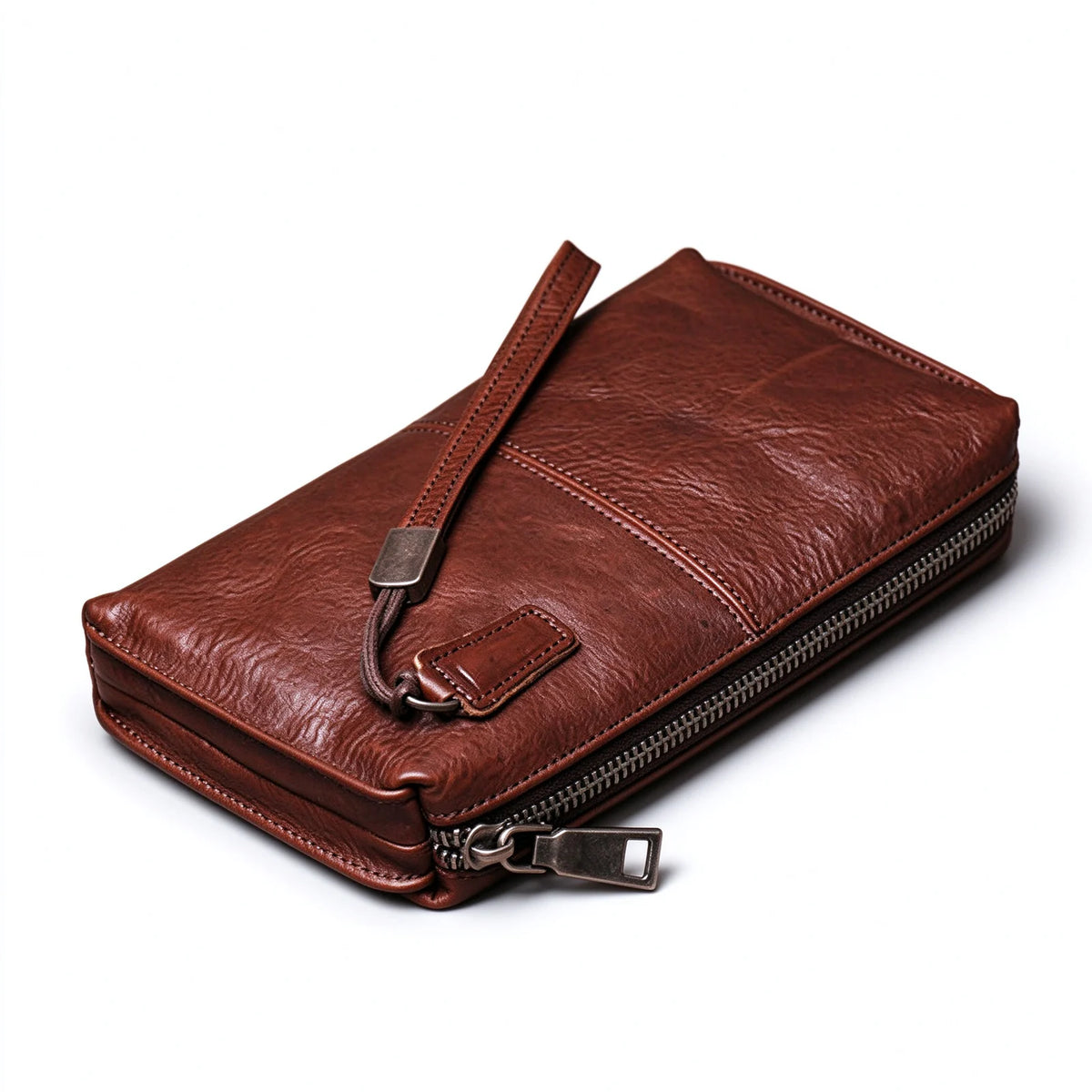 Angled view of a red-brown leather long wallet showing its zip edge and wrist loop