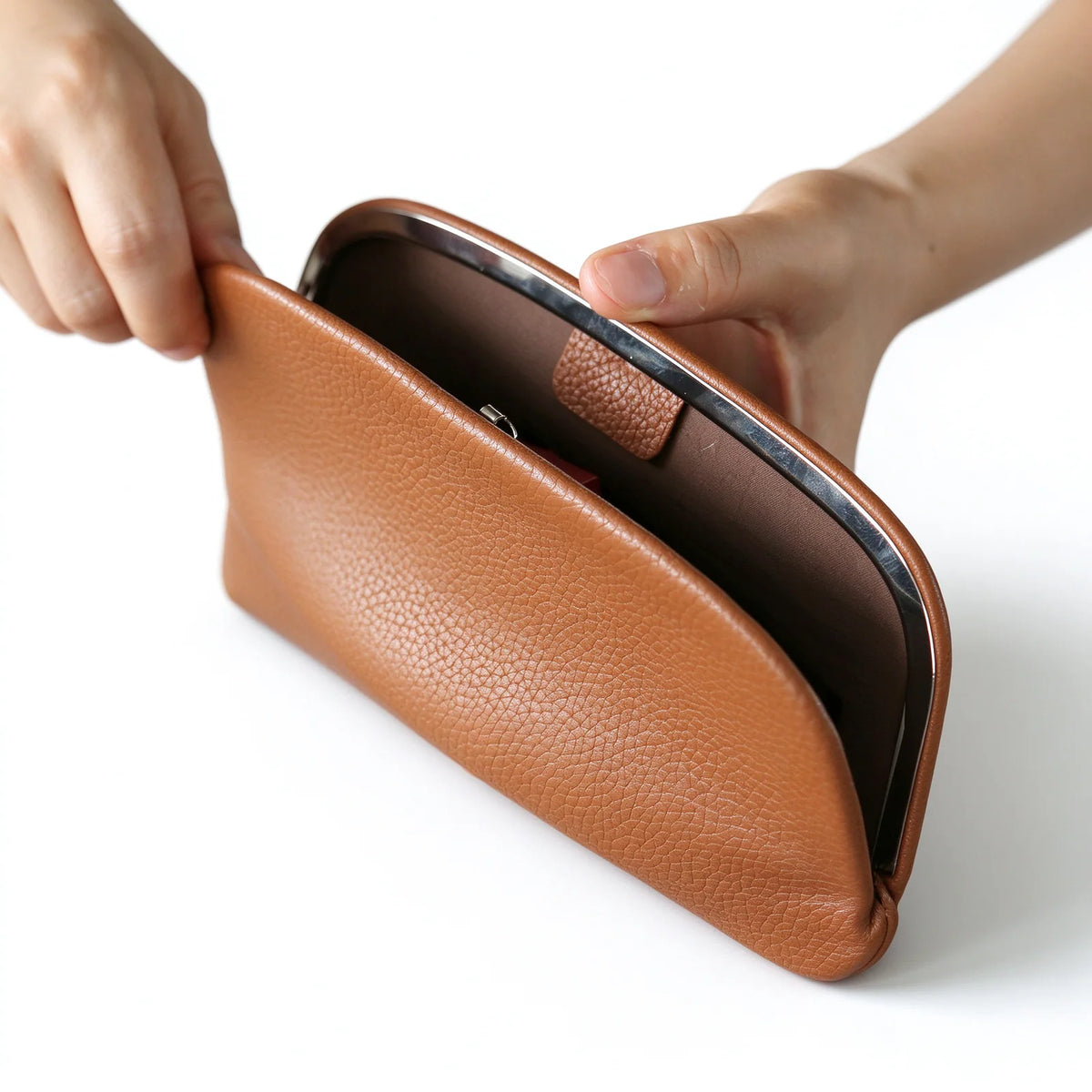 Open tan leather clutch pouch showing the silver-tone metal frame and brown interior