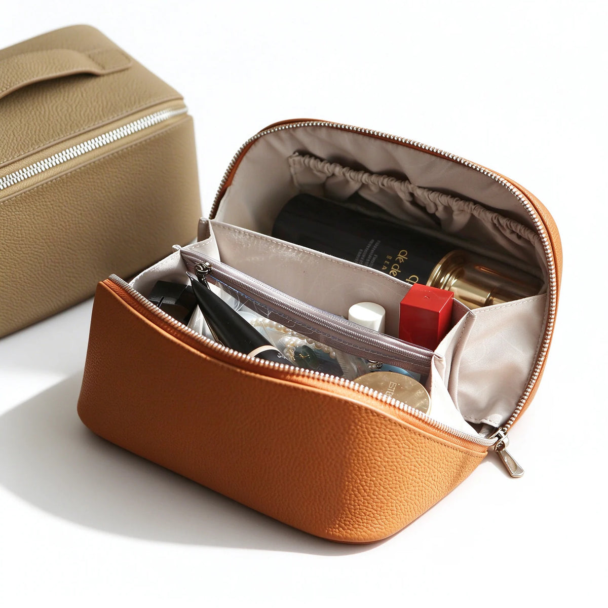 Open orange leather makeup bag showing pale lining, interior pockets and a zippered divider holding cosmetics.