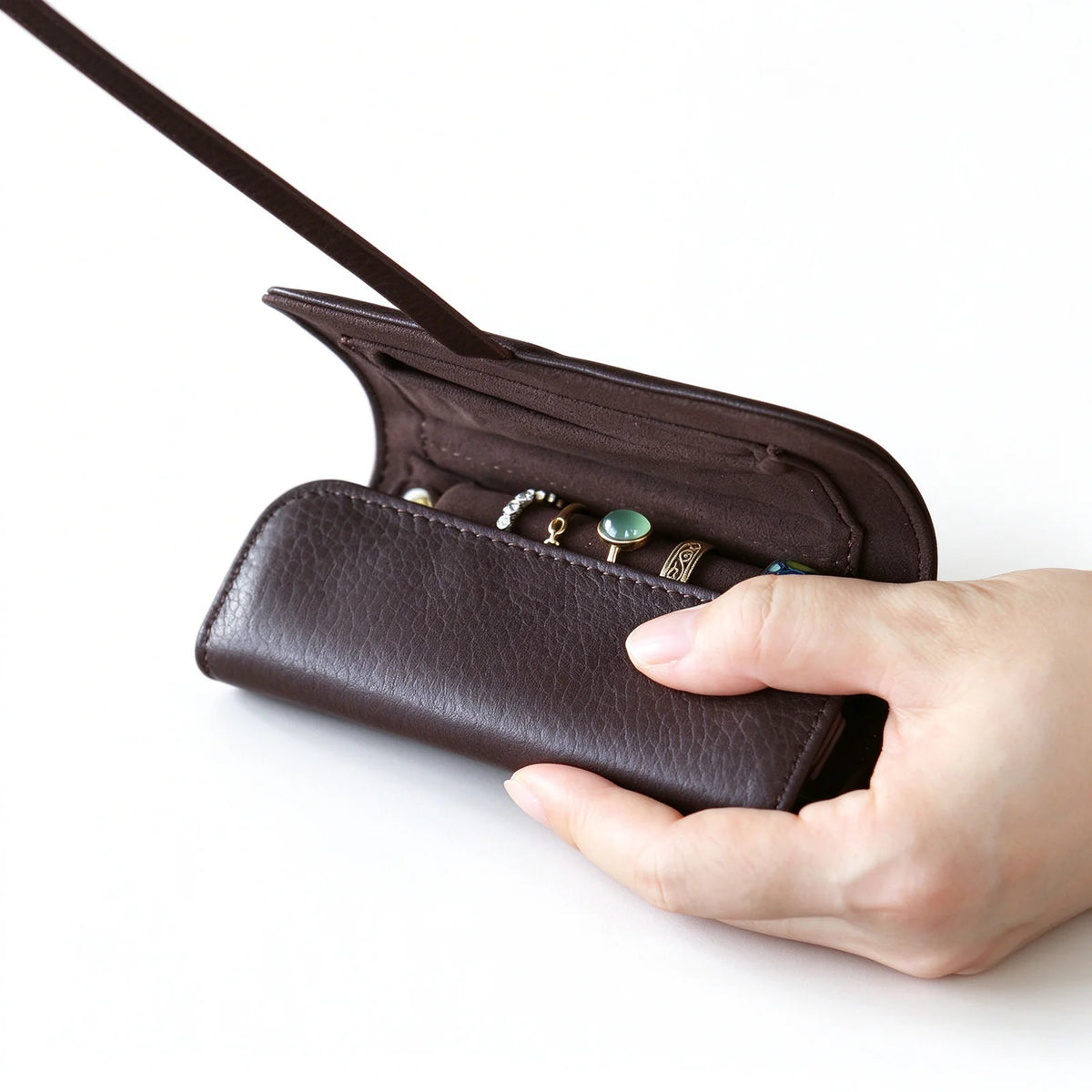Dark brown leather jewelry roll opened to show rings on the interior ring bar