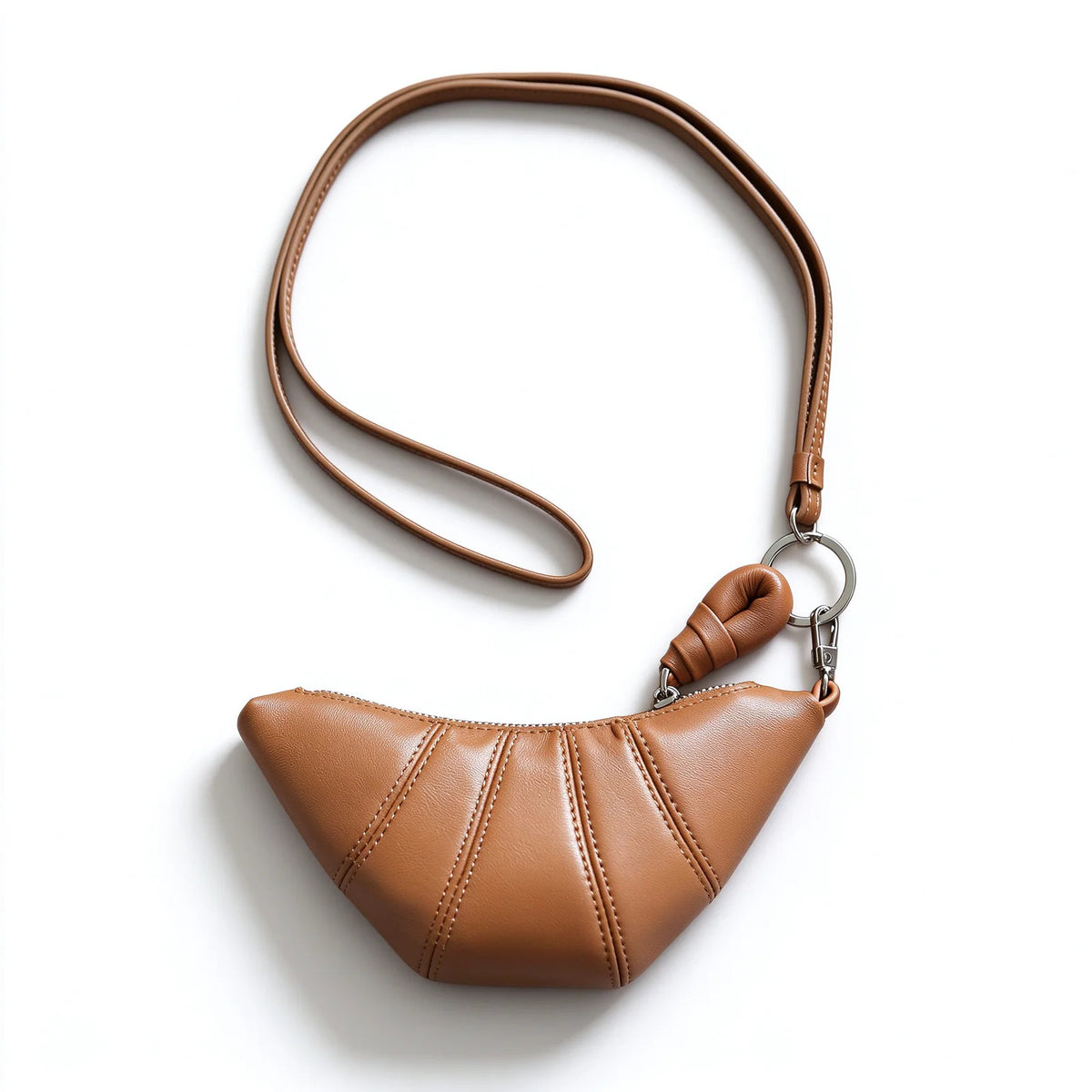 Tan crescent leather pouch displayed with a long thin matching strap attached by a silver-tone clip and ring.