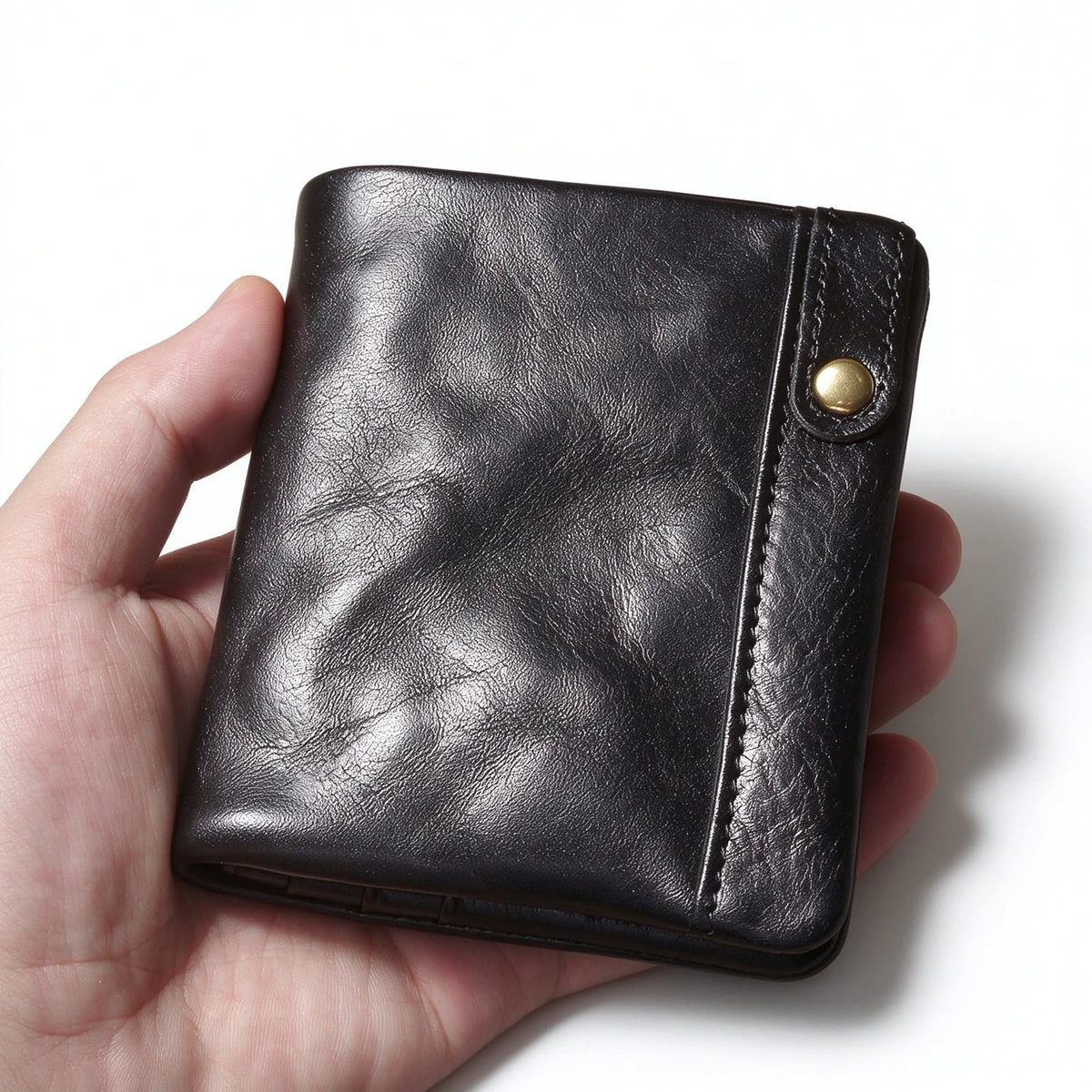 Black leather card and coin wallet held in one hand, with a narrow snap-fastened tab at the edge.