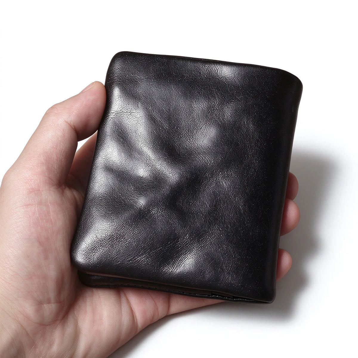 Back view of a hand-held black leather wallet showing the plain panel and folded bottom edge.