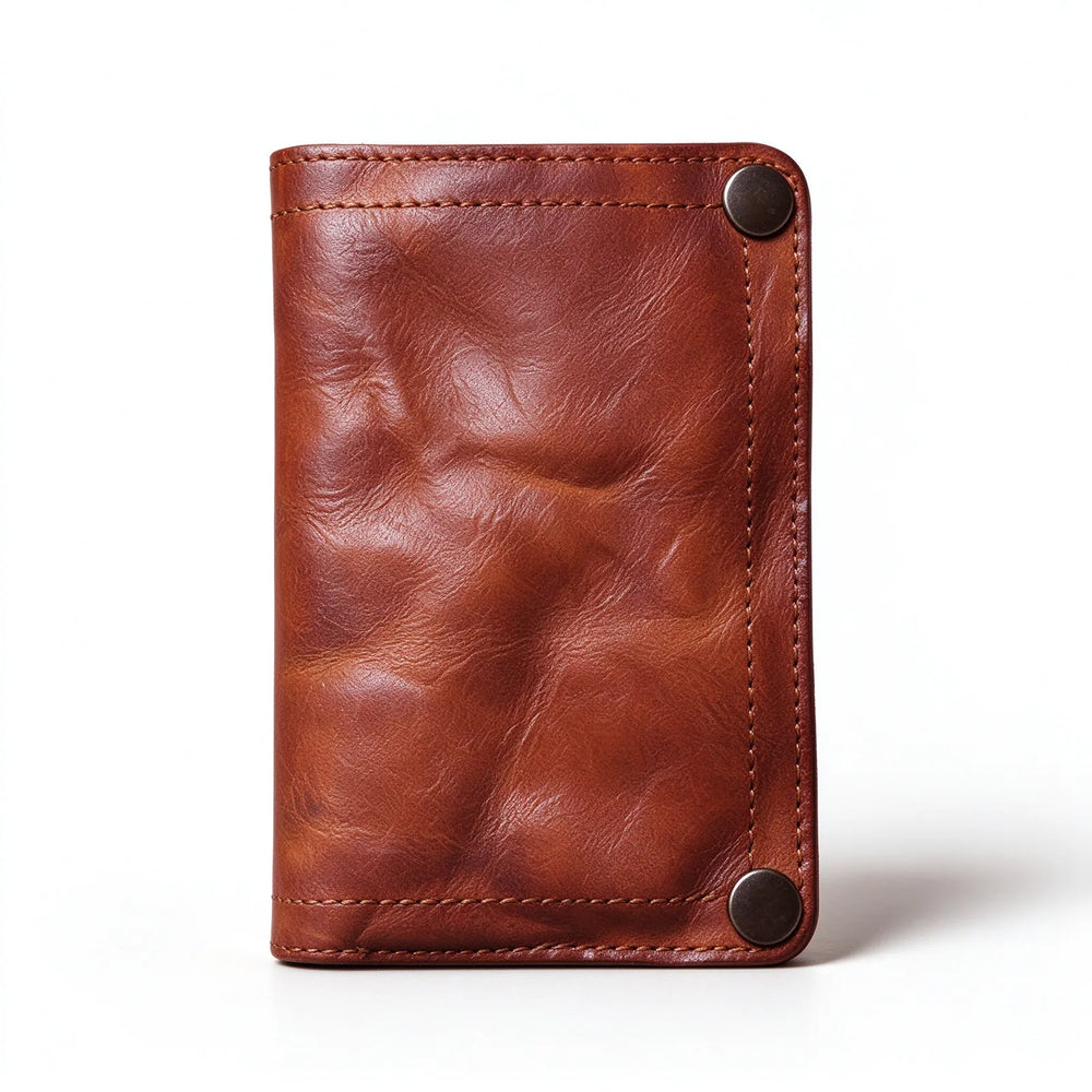 Brown leather bifold wallet standing upright with two corner snap fasteners and visible edge stitching.