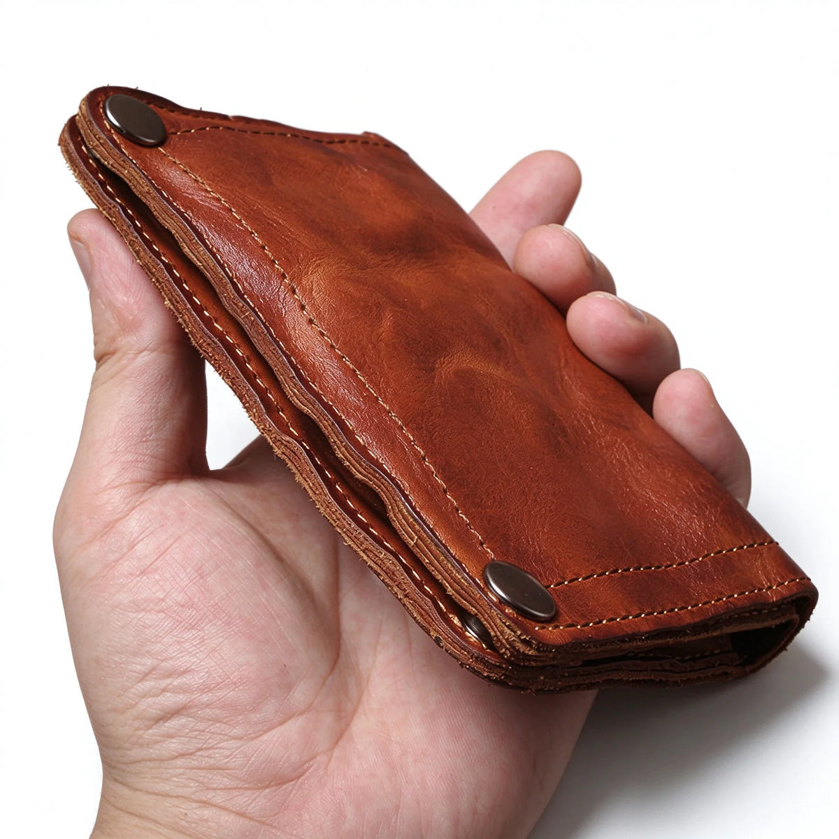 Side view of a folded brown leather wallet showing the layered construction and stitched edges.