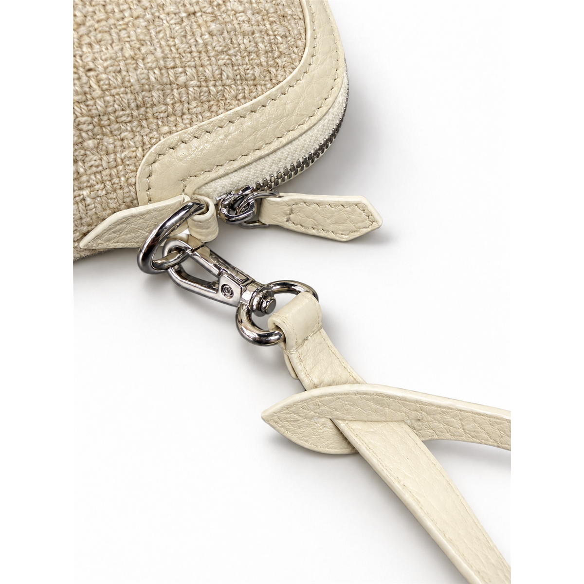 Close-up of the coin purse zipper pull and silver-tone clasp attaching the light-colored wrist strap.